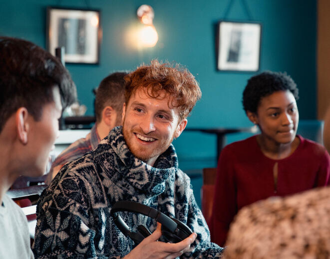 Mixed group of seated students socialising indoors Mixed group of seated students socialising indoors